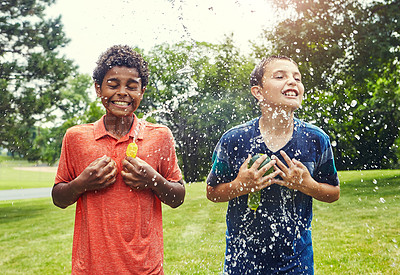 Buy stock photo Shot of adorable young boys playing with water balloons outdoors