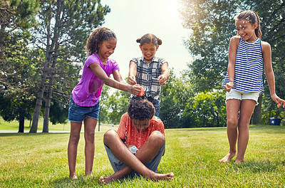 Buy stock photo Shot of adorable children playing with water balloons outdoors