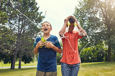 Buy stock photo Shot of adorable young boys playing with water balloons outdoors