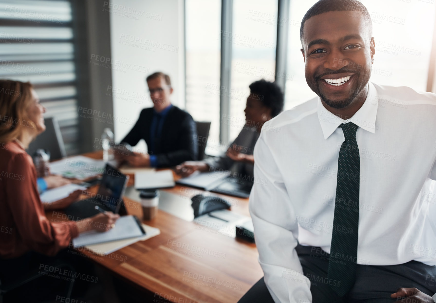 Buy stock photo Portrait of a confident businessman sitting in an office with his colleagues in the background
