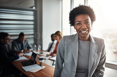 Buy stock photo Portrait of a confident young businesswoman standing in an office with her colleagues in the background