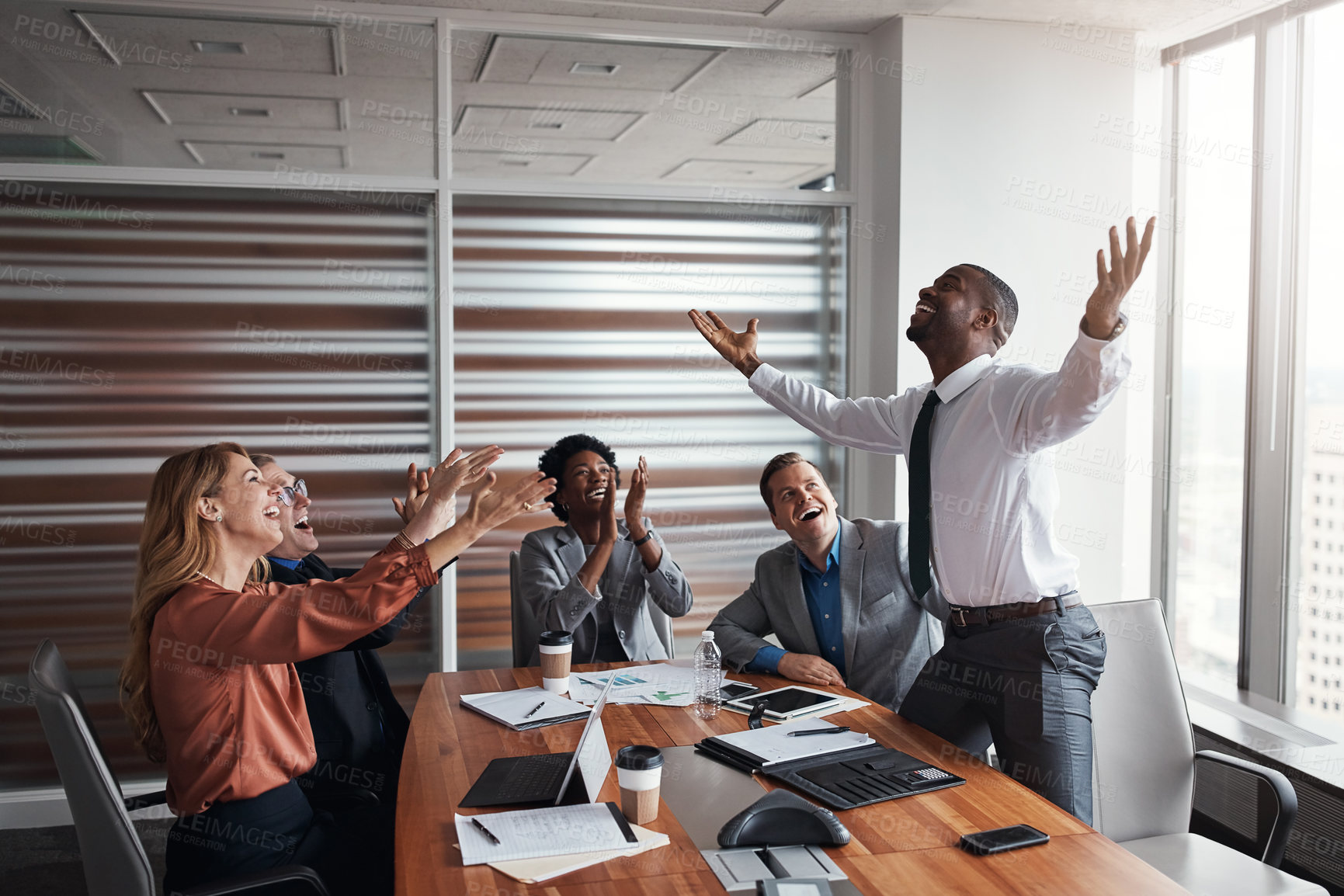 Buy stock photo Shot of a group of businesspeople cheering a colleague in an office