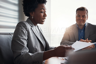Buy stock photo Shot of two businesspeople going through paperwork in an office