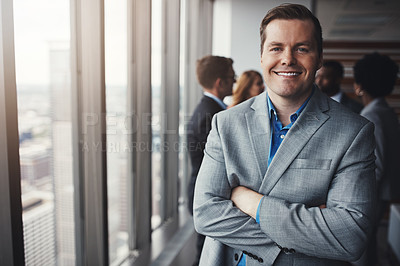 Buy stock photo Portrait of a professional businessman standing in an office with colleagues in the background