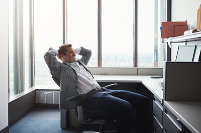 Buy stock photo Shot of a businessman looking relaxed while sitting at his desk