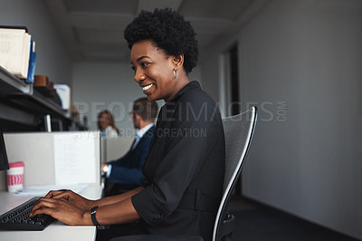 Buy stock photo Shot of a businesswoman sitting at her desk with colleagues in the background