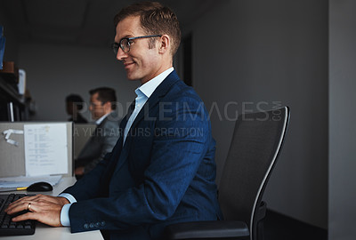 Buy stock photo Shot of a businessman sitting at his desk with colleagues in the background