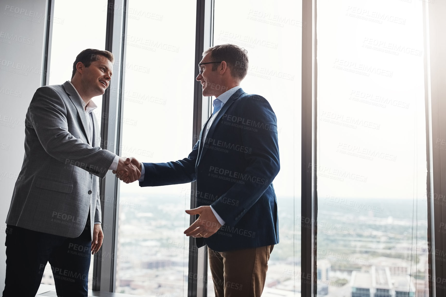 Buy stock photo Low angle shot of two corporate businessmen shaking hands during a meeting in the boardroom