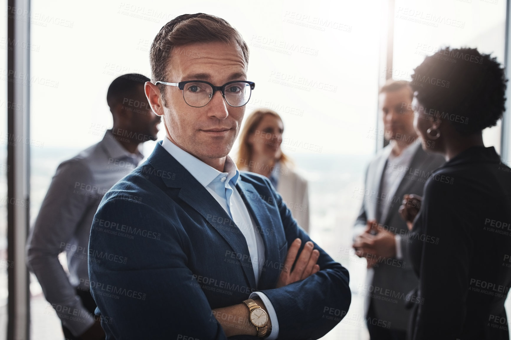 Buy stock photo Cropped portrait of a handsome businessman standing with his arms folded during a meeting in the boardroom