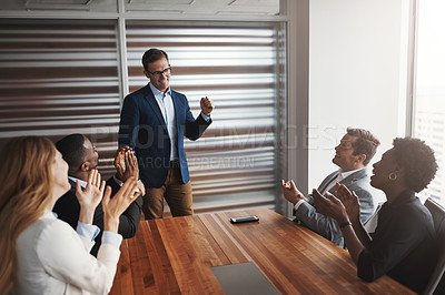 Buy stock photo Shot of a group of businesspeople applauding a colleague in an office