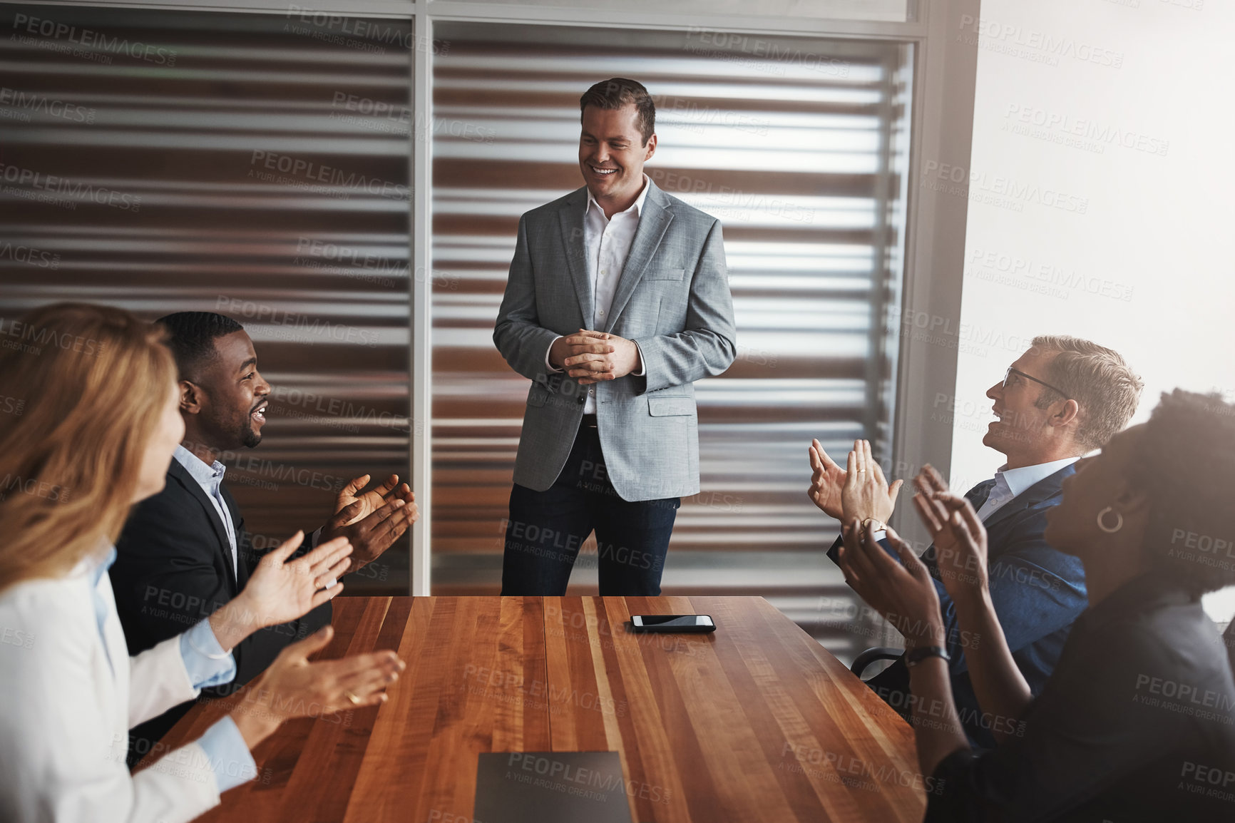 Buy stock photo Shot of a group of businesspeople applauding a colleague in an office