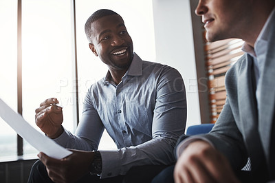 Buy stock photo Shot of two businessmen going through paperwork in an office