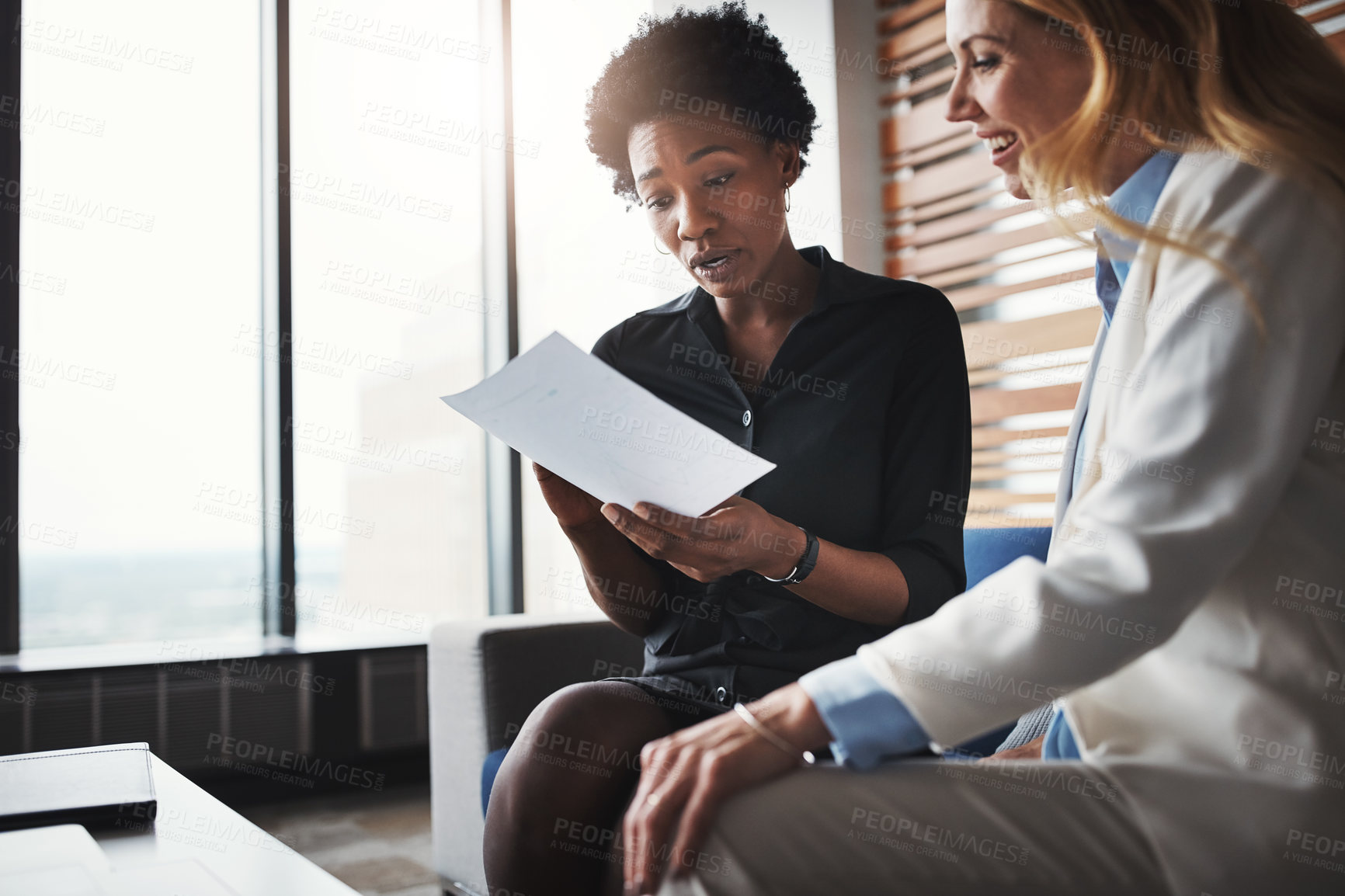 Buy stock photo Shot of two businesswomen going through paperwork in an office