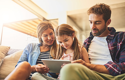 Buy stock photo Shot of a mother and father using a digital tablet with their daughter on the sofa at home