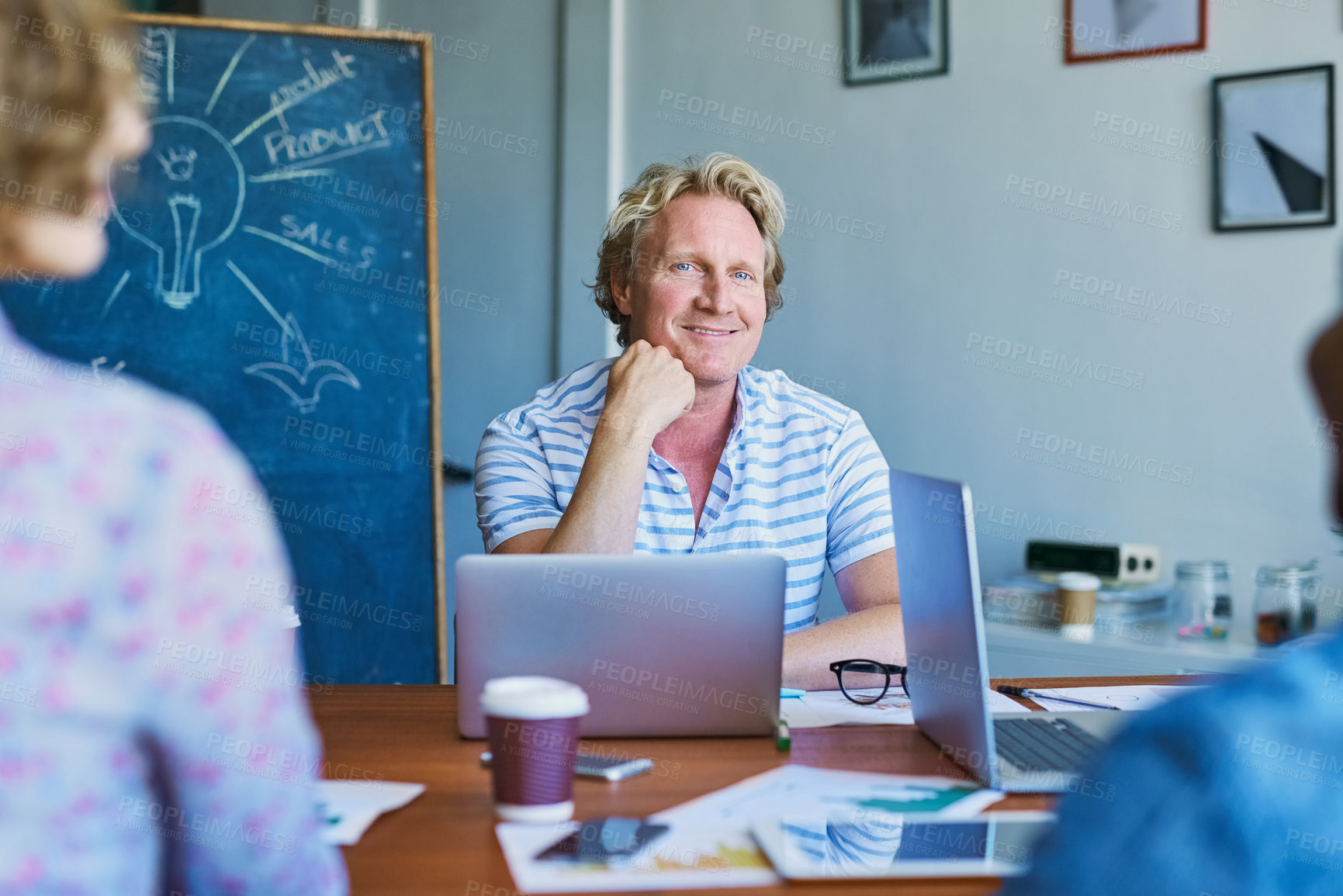Buy stock photo Portrait of a mature man sitting in on a meeting with his team in a modern office