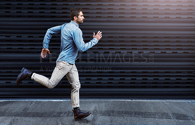 Buy stock photo Shot of a handsome young man running in the city