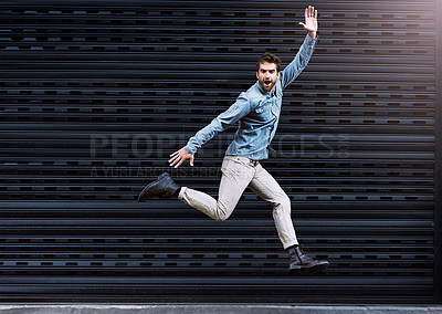 Buy stock photo Man, jump and wave on dark background for energy, positive emotion and carefree in urban city. Young people, excited and cheerful body gesture for joy, happy and fun movement in air with mockup 