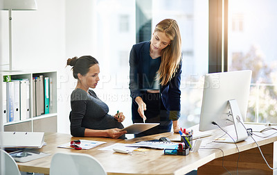 Buy stock photo Shot of a pregnant businesswoman and a colleague using a digital tablet in their office