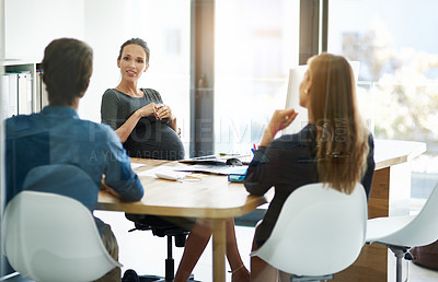 Buy stock photo Cropped shot of a pregnant businesswoman having a meeting with two colleagues in her office