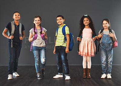 Buy stock photo Studio portrait of a diverse group of kids carrying their school backpacks against a gray background