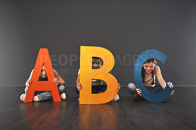 Buy stock photo Studio portrait of a diverse group of kids holding up letters of the alphabet against a gray background
