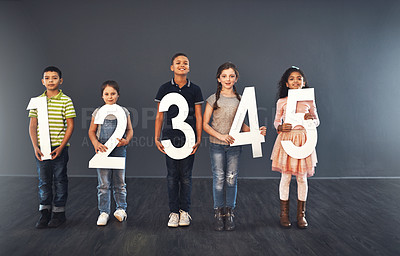 Buy stock photo Studio portrait of a diverse group of kids holding up numbers against a gray background