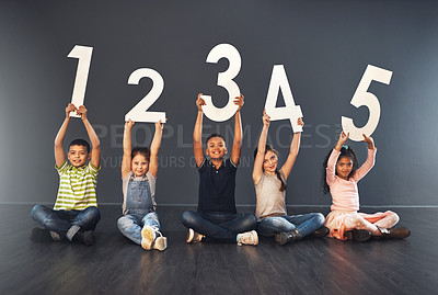 Buy stock photo Studio portrait of a diverse group of kids holding up numbers against a gray background