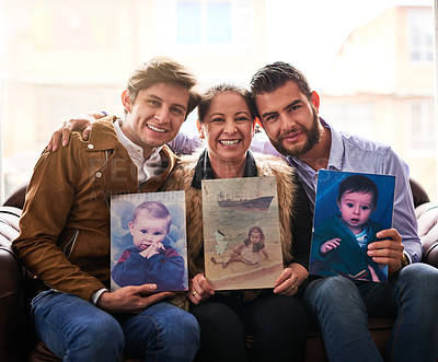 Buy stock photo Shot of a mother and son's holding old photographs of themselves as children at home