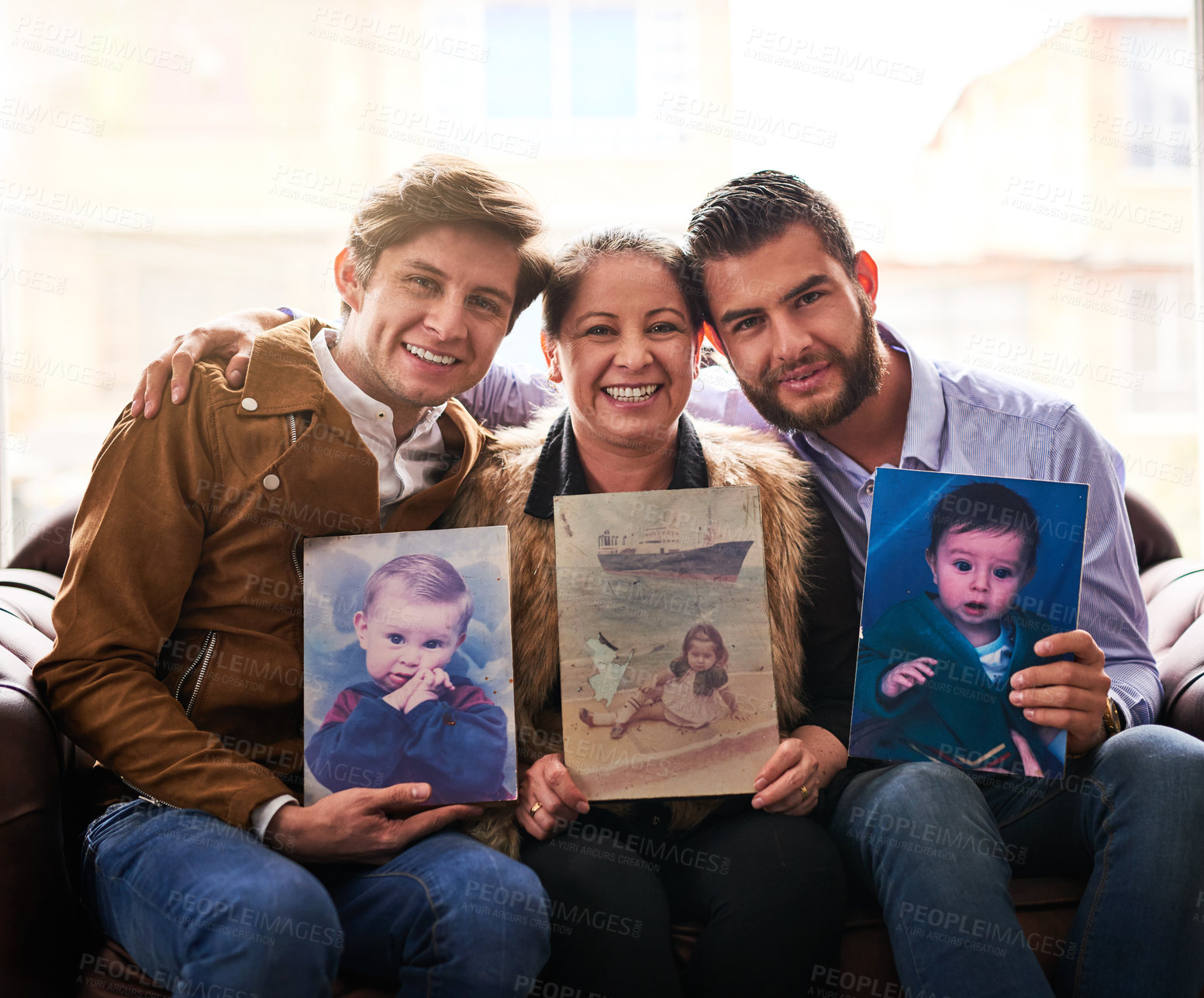 Buy stock photo Shot of a mother and son's holding old photographs of themselves as children at home