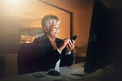 Buy stock photo Shot of a mature businesswoman using a mobile phone at her desk during a late night at work