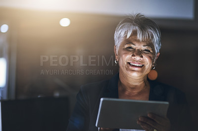 Buy stock photo Shot of a mature businesswoman using a digital tablet late at night in a modern office