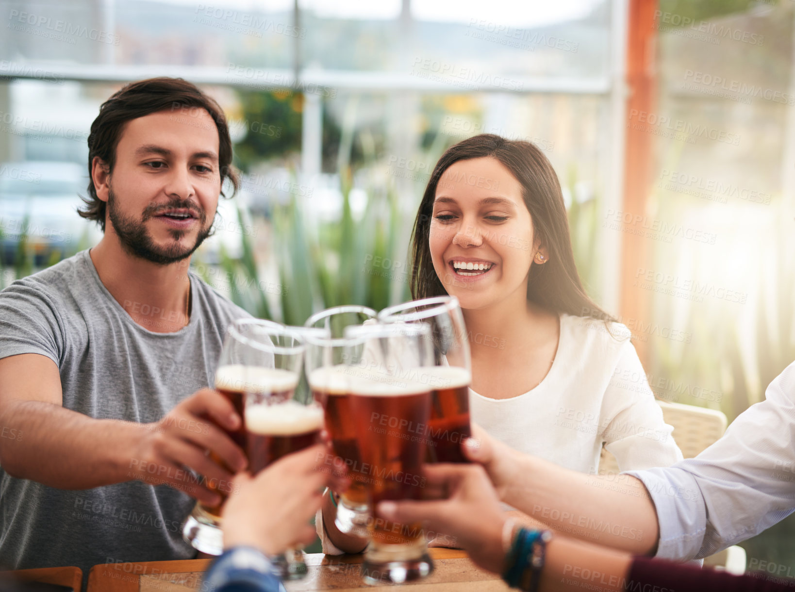 Buy stock photo Shot of a group of young business colleagues having a celebratory toast with beer around a table outside