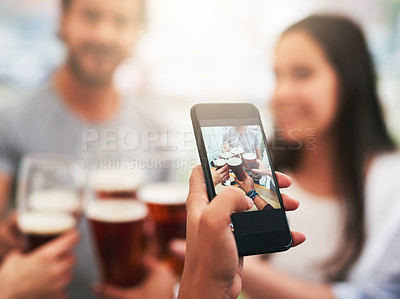 Buy stock photo Shot of a unrecognizable person taking a photo with their phone of a group young people celebrating with drinks