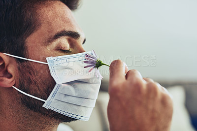 Buy stock photo Closeup of a cheerful unrecognisable man wearing a protective mask and smelling a flower eye's closed