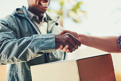 Buy stock photo Closeup shot of a courier shaking hands with a customer while making a home delivery