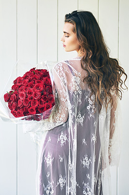 Buy stock photo Rearview shot of a beautiful young woman standing with her eyes closed while holding a bouquet of roses outside