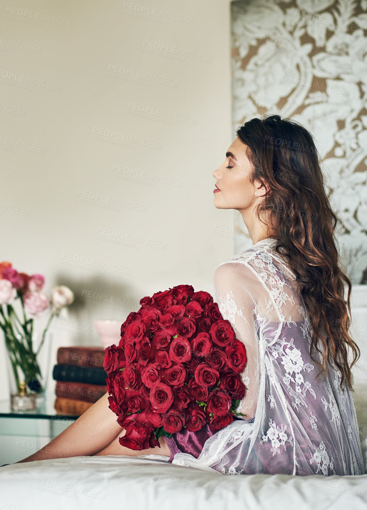 Buy stock photo Rearview shot of a beautiful young woman relaxing on her bed while holding a bouquet of roses