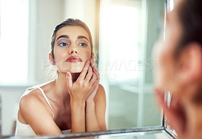 Buy stock photo Shot of an attractive young woman inspecting her skin in the mirror