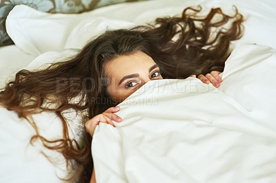 Buy stock photo High angle portrait of an attractive young woman lying under the covers in bed