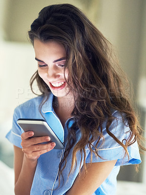 Buy stock photo Cropped shot of an attractive young woman sending a text while sitting on her bed