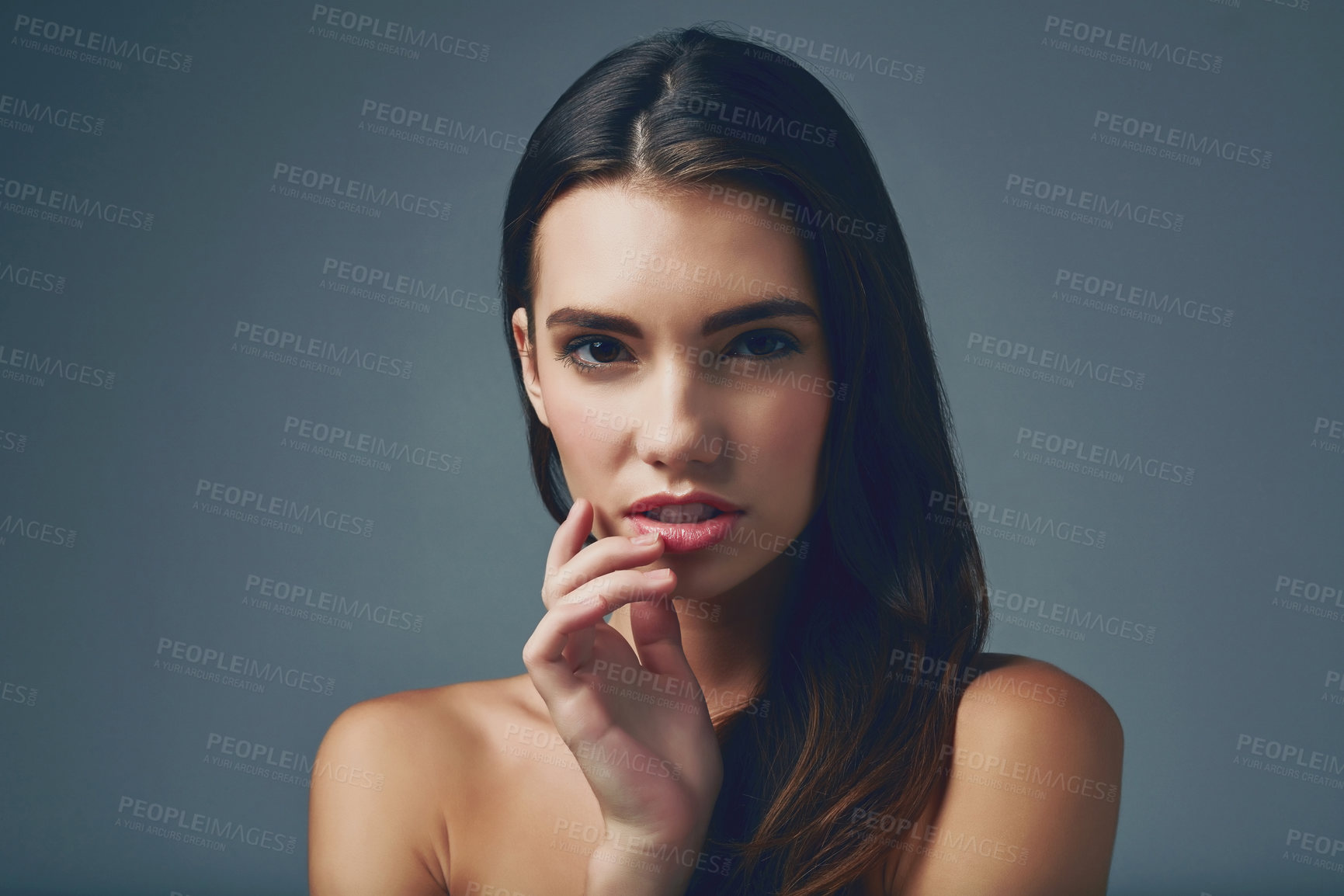 Buy stock photo Studio portrait of a beautiful young woman posing against a blue background