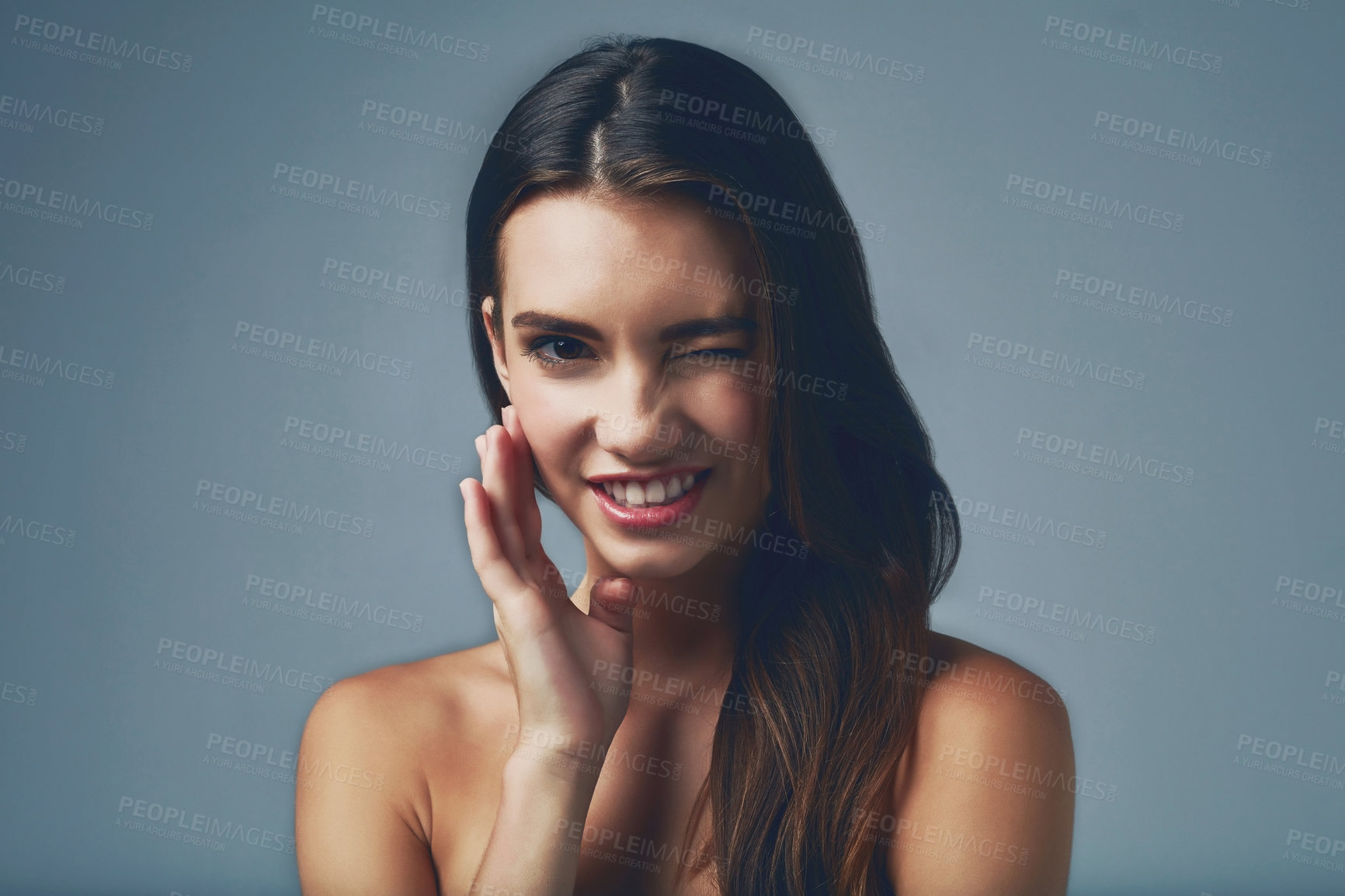 Buy stock photo Beauty, wink and portrait of girl for skincare on grey background for smooth face, detox or natural glow. Flirting, smile and happy woman in studio with cosmetics, shine or transformation results