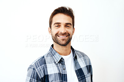 Buy stock photo Studio portrait of a cheerful young man standing against a white background while looking directly at the camera