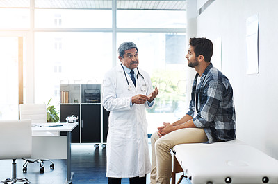 Buy stock photo Shot of a mature male doctor and patient having a discussion in the doctor's office before a checkup