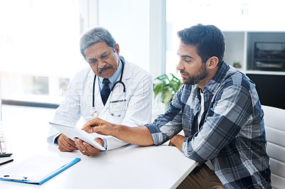 Buy stock photo Shot of a mature male doctor and patient having a discussion in the doctor's office before a checkup