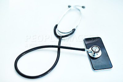 Buy stock photo Shot of a stethoscope lying on top of a mobile phone against a white background