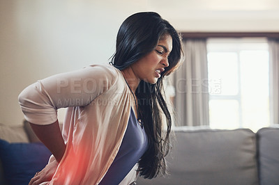 Buy stock photo Shot of a young woman suffering with backache at home