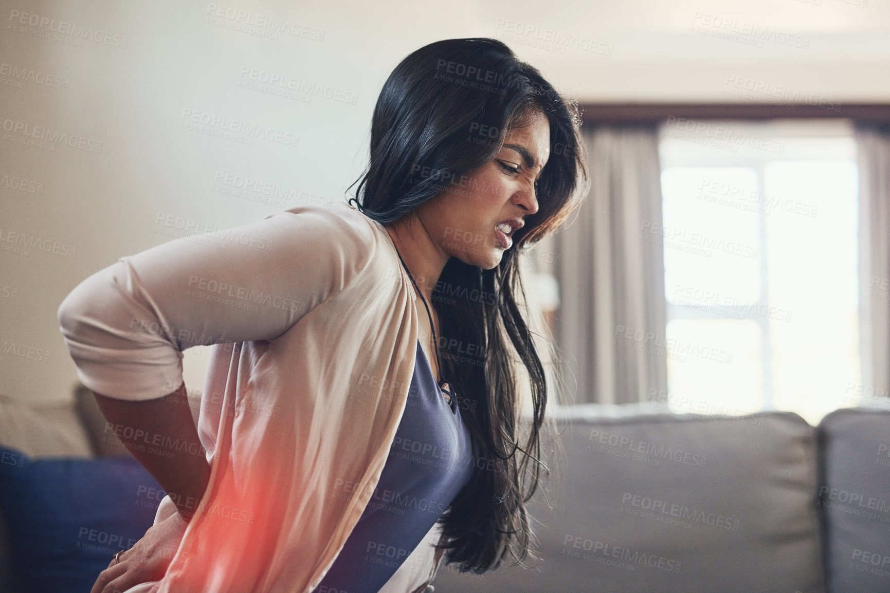 Buy stock photo Shot of a young woman suffering with backache at home