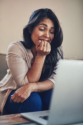 Buy stock photo Shot of a young woman biting her nails while working on a laptop at home