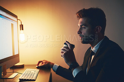 Buy stock photo Cropped shot of a young businessman drinking coffee while working late in the office